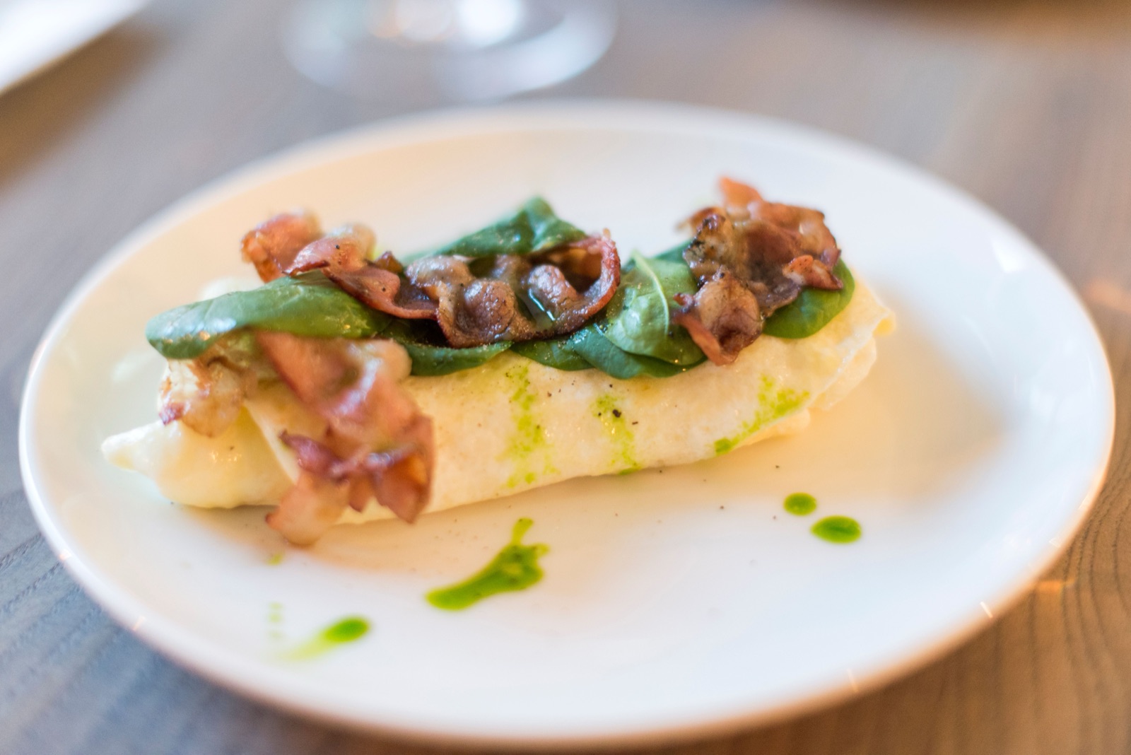 hvit fisk med sprø bacon og spinat på en tallerken
